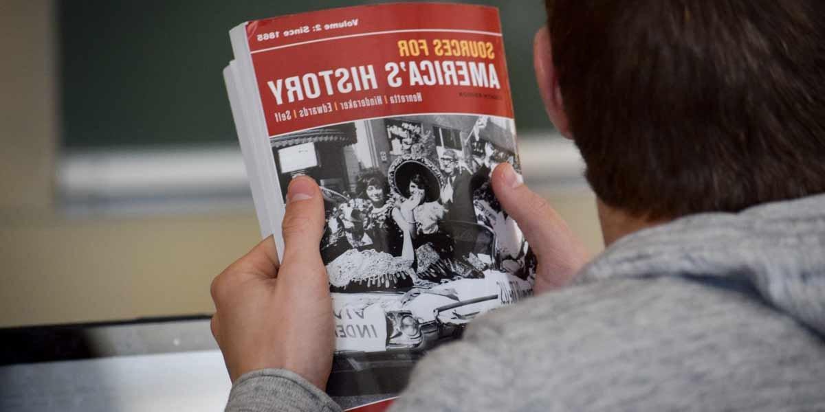 一个学生在课堂上拿着一本历史教科书